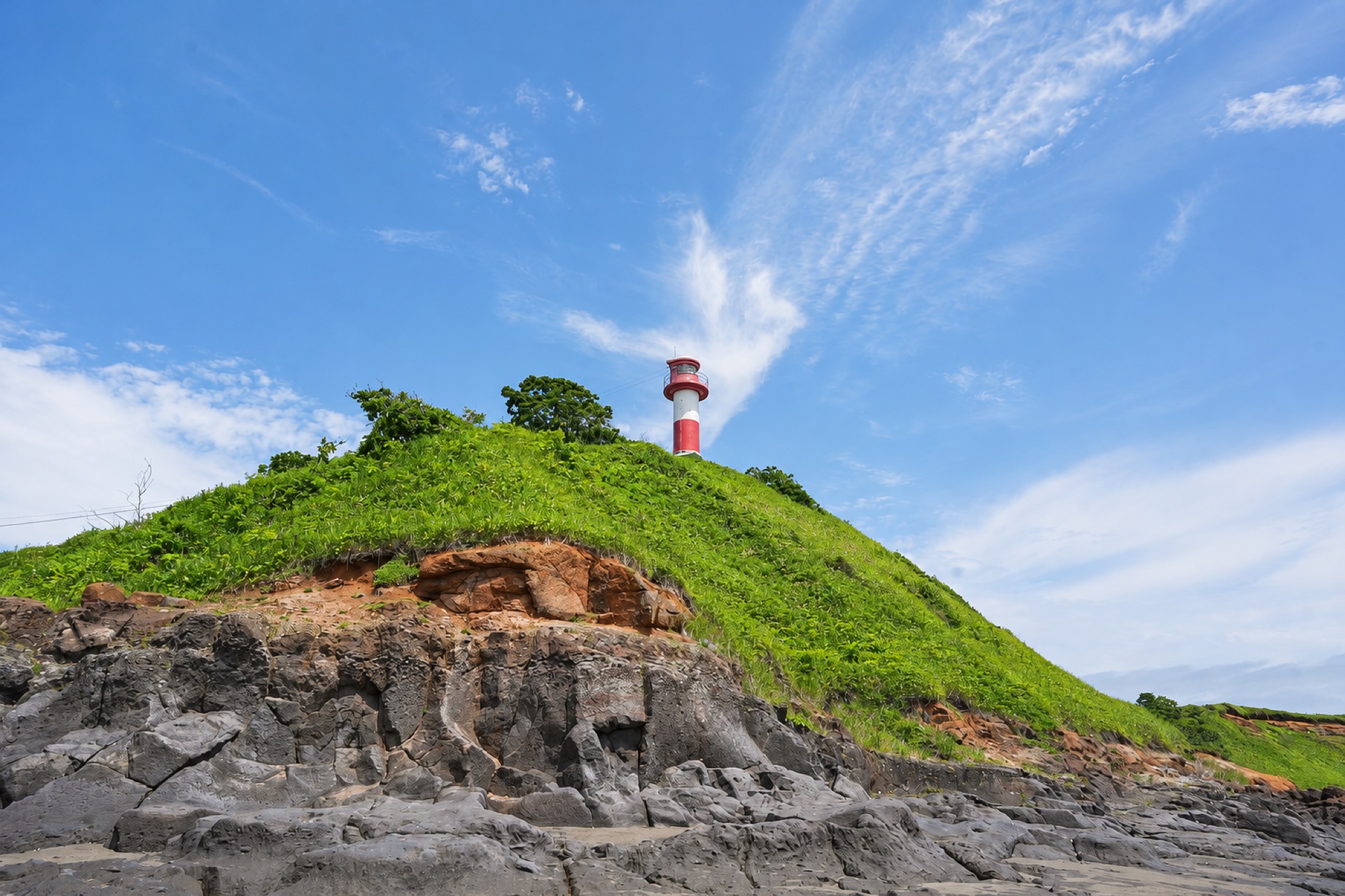 アヨロ海岸の岩場と海、灯台のある風景